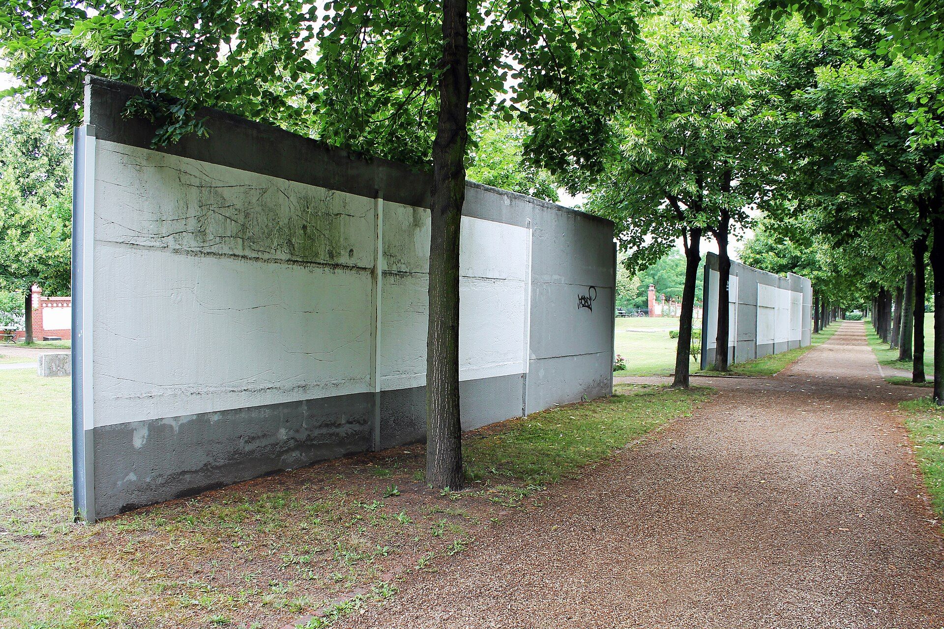 Surviving white-and-grey hinterland barrier among trees in the Invalids’ Cemetery