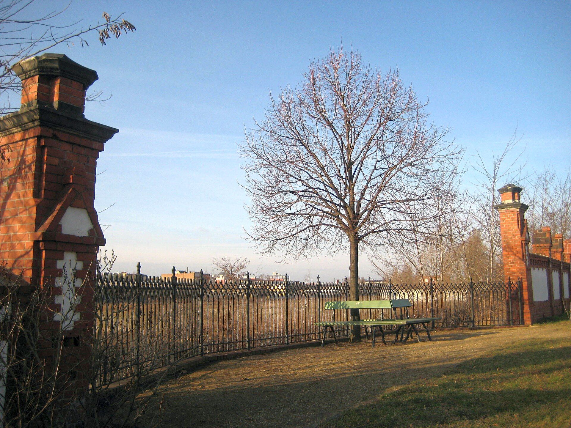 Reconstructed red-brick wall, iron railing and Königslinde tree at the Invalids’ Cemetery
