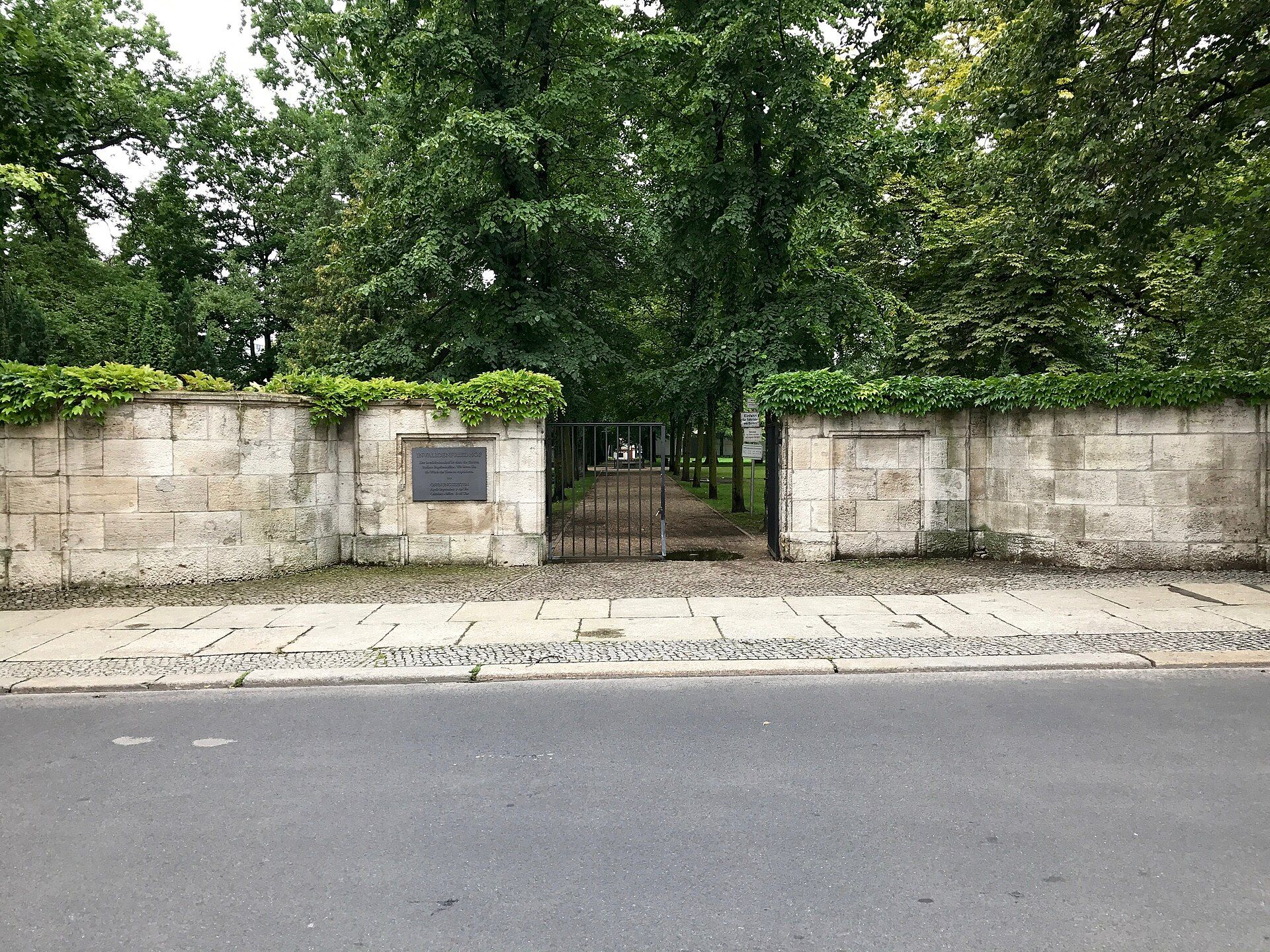Ivy-covered cemetery wall and open metal gate of the Invalids’ Cemetery on Scharnhorststraße